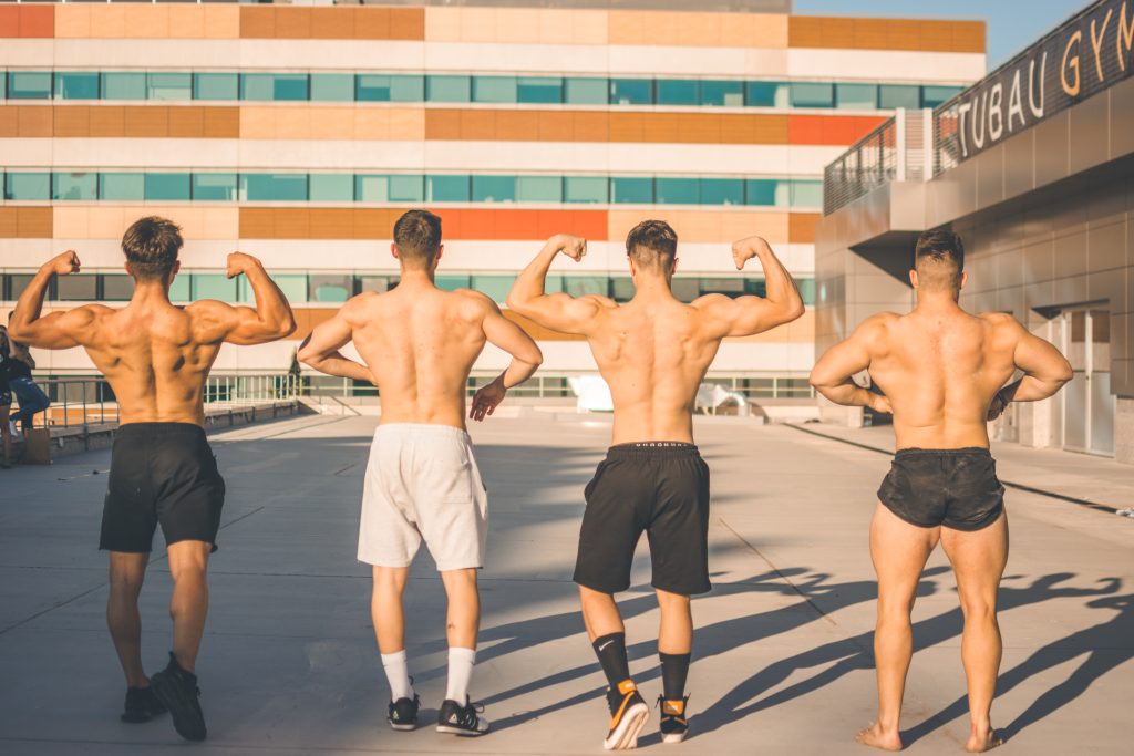 atletas de espalda haciendo poses de culturismo tras realizan un entrenamiento de peso libre con allfreeweight